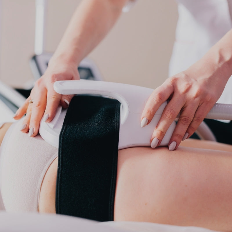 Person receiving em sculpt treatment in clinic