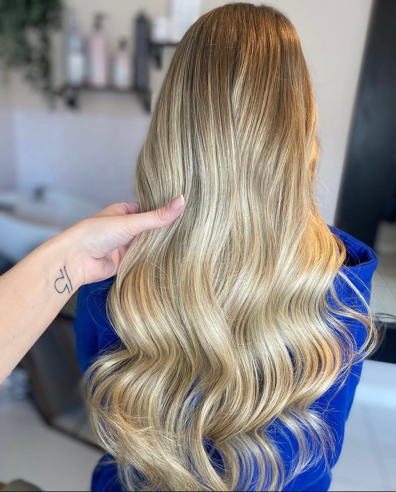 Blonde hair with wavy texture held by a hand in a salon setting