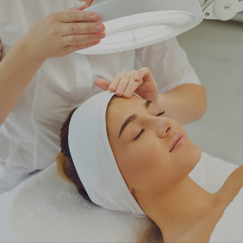 Woman receiving a facial treatment with a professional in a clinical setting